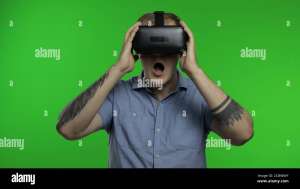 Amazed man using VR app headset helmet to play simulation game